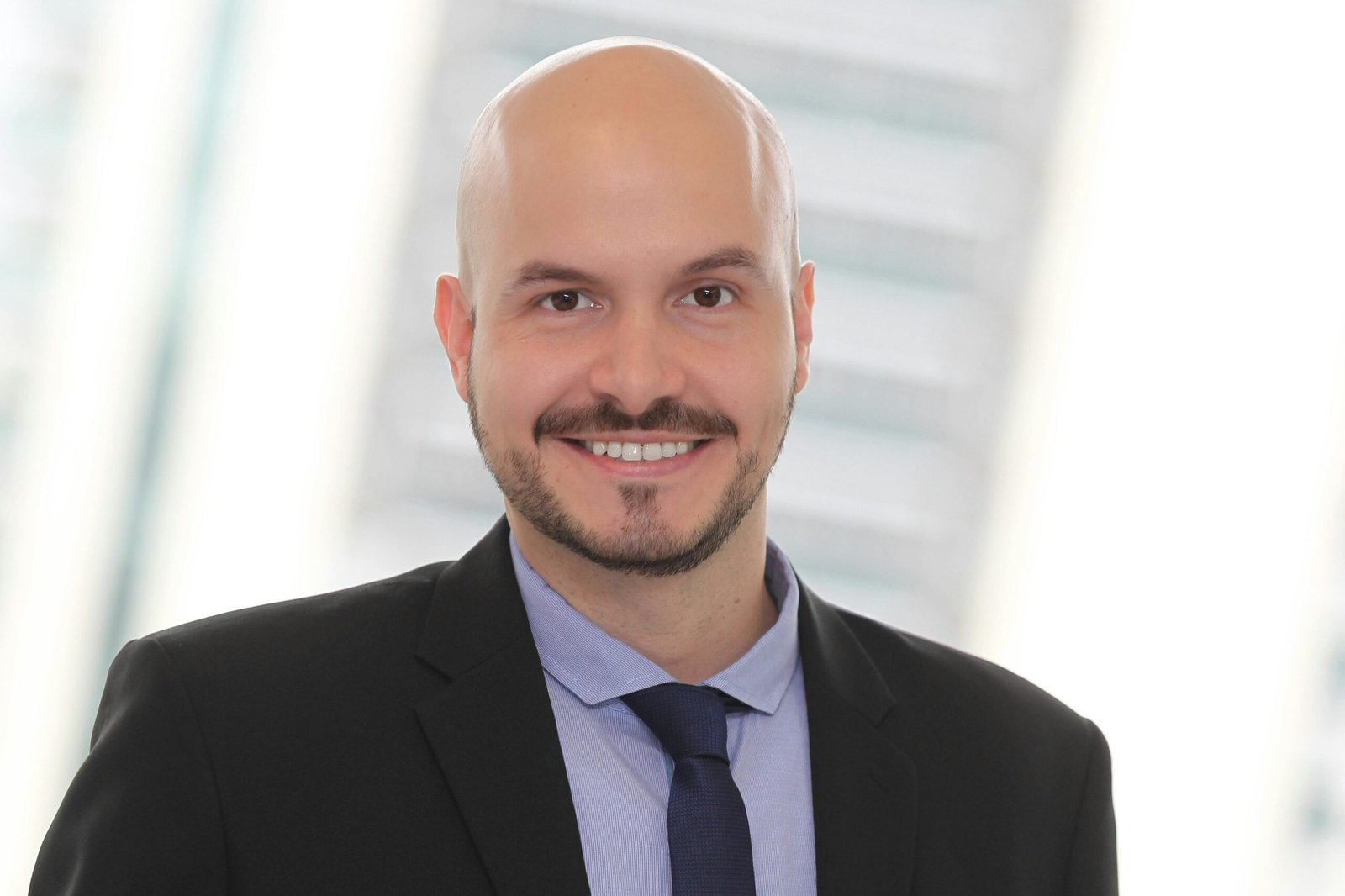 A confident bald man in a suit smiling, ideal for business contexts.
